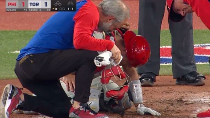 Philadelphia Phillies catcher J.T. Realmuto doubles over in pain from a pitch hitting him in the groin area.