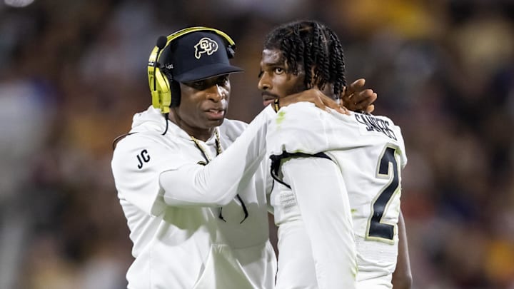 Colorado coach Deion Sanders talks to his son and quarterback Shedeur Sanders in between plays.