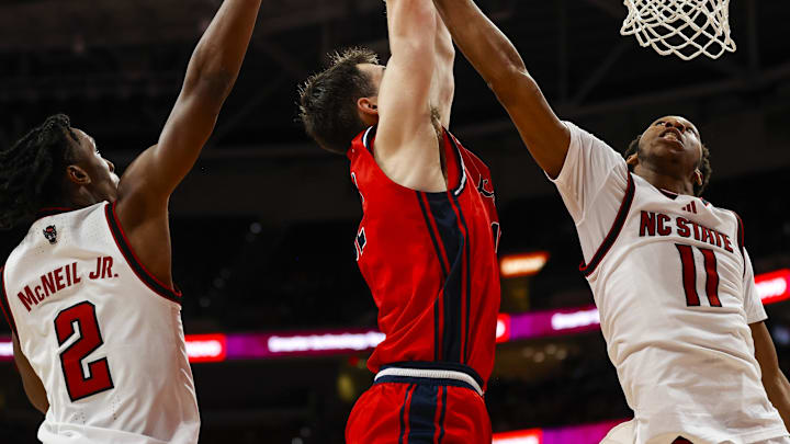 Dec 6, 2025; Raleigh, North Carolina, USA; Liberty Flames forward Josh Smith (12) attempts a dunk but is blocked by NC State Wolfpack guard Jr. Paul McNeil (2) and guard Quadir Copeland (11) during the second half of the game at Lenovo Center. Mandatory Credit: Jaylynn Nash-Imagn Images