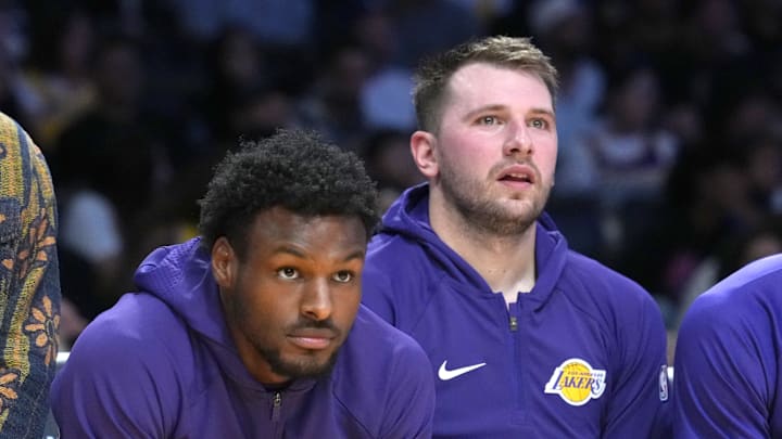 Oct 24, 2025; Los Angeles, California, USA; Los Angeles Lakers forward LeBron James (left), guard Bronny James (center) and guard Luka Doncic watch from the bench in the first half against the Minnesota Timberwolves at Crypto.com Arena. Mandatory Credit: Kirby Lee-Imagn Images