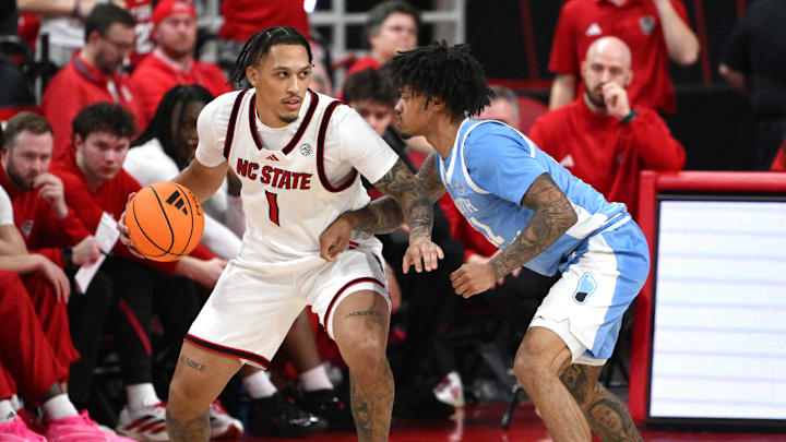 Feb 17, 2026; Raleigh, North Carolina, USA;  NC State Wolfpack forward Darrion Williams (1) controls the ball against North Carolina Tar Heels guard Jonathan Powell (11) during the second half at Lenovo Center. Mandatory Credit: Zachary Taft-Imagn Images