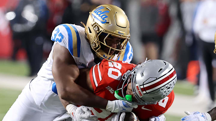 Nov 15, 2025; Columbus, Ohio, USA; Ohio State Buckeyes running back James Peoples (20) runs the ball as UCLA Bruins linebacker Isaiah Chisom (32) makes the tackle during the fourth quarter at Ohio Stadium. Mandatory Credit: Joseph Maiorana-Imagn Images