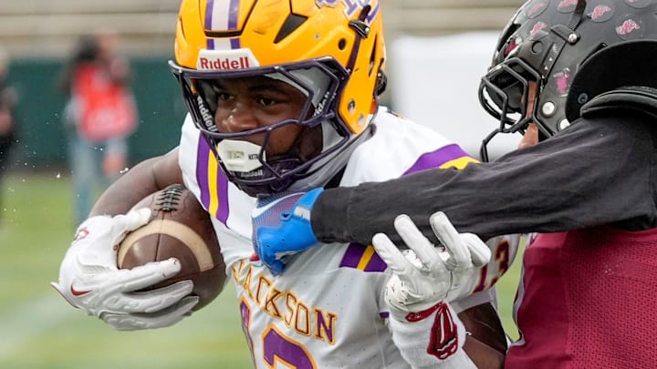 Dec 5, 2025; Birmingham, AL, USA; Jackson's EJ Crowell (13) breaks through a tackle by Anniston's Dakyus Baker (7) on his way to the first of three touchdown runs in the first half at Protective Life Stadium in the AHSAA 4A State Championship game.
