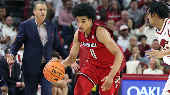 Dec 3, 2025; Fayetteville, Arkansas, USA; Louisville Cardinals guard Mikel Brown Jr (0) drives against Arkansas Razorbacks guard D.J. Wagner (21) as head coach John Calipari watches during the second half at Bud Walton Arena. Arkansas won 89-80. Mandatory Credit: Nelson Chenault-Imagn Images