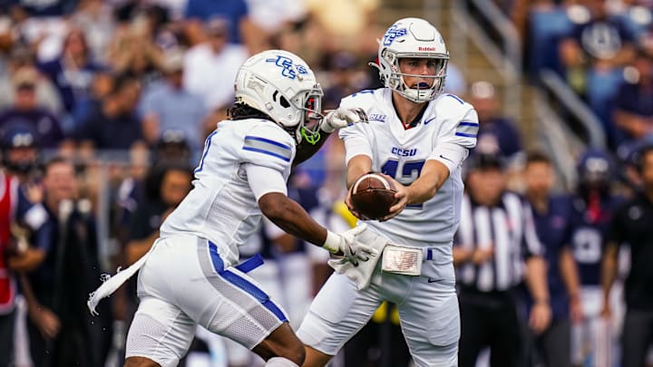 Aug 30, 2025; East Hartford, Connecticut, USA; Central Connecticut State Blue Devils quarterback Brady Olson (12) hands off the ball to running back Elijah Howard (7) against the Connecticut Huskies in the first quarter at Pratt & Whitney Stadium at Rentschler Field. Mandatory Credit: David Butler II-Imagn Images