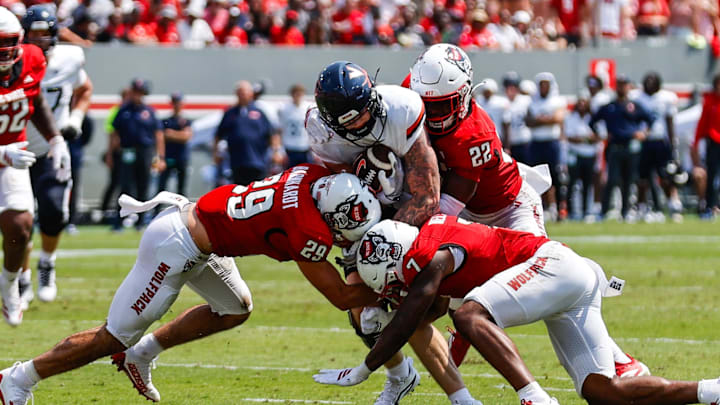 Sep 6, 2025; Raleigh, North Carolina, USA; Virginia Cavaliers tight end Sage Ennis (0) is tackled by North Carolina State Wolfpack safety Brody Barnhardt (29), cornerback Brian Nelson II (7) and cornerback Jackson Vick (22) during the first half of the game at Carter-Finley Stadium. Mandatory Credit: Jaylynn Nash-Imagn Images Sep 6, 2025; Raleigh, North Carolina, USA; Virginia Cavaliers tight end Sage Ennis (0) is tackled by North Carolina State Wolfpack safety Brody Barnhardt (29), cornerback Brian Nelson II (7) and cornerback Jackson Vick (22) during the first half of the game at Carter-Finley Stadium. Mandatory Credit: Jaylynn Nash-Imagn Images