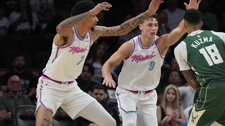 Apr 5, 2025; Miami, Florida, USA;  Milwaukee Bucks forward Kyle Kuzma (18) looks to take a shot as Miami Heat and guard Pelle Larsson (9) and center Kel'el Ware (7) defend on the play during the first half at Kaseya Center. Mandatory Credit: Jim Rassol-Imagn Images