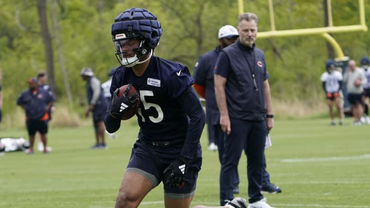 Rome Odunze catches a throw at minicamp as coach Matt Eberflus looks on. Odunze signed his four-year rookie contract with an option for Year 5 on Tuesday.
