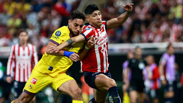 El uruguayo Sebastián Cáceres del América y Alan Pulido de Chivas compiten por el esférico