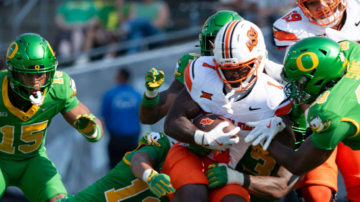 Oklahoma State running back Kalib Hicks is brought down by a pack of Oregon defenders as the Oregon Ducks host the Oklahoma State Cowboys on Sept. 6, 2025, at Autzen Stadium in Eugene, Oregon.