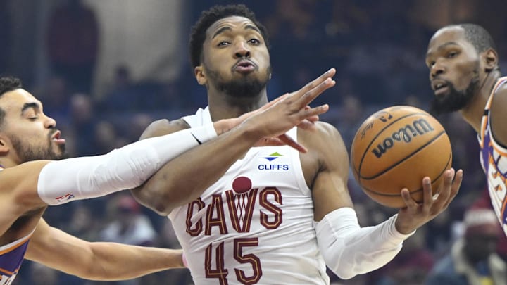 Jan 20, 2025; Cleveland, Ohio, USA; Cleveland Cavaliers guard Donovan Mitchell (45) drives between Phoenix Suns guard Tyus Jones (21) and forward Kevin Durant (35) in the first quarter at Rocket Mortgage FieldHouse. Mandatory Credit: David Richard-Imagn Images