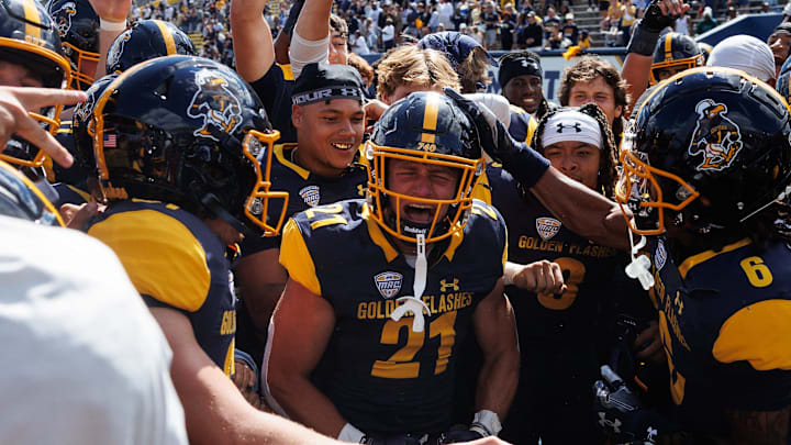 Kent State running back Cade Wolford rings the Victory Bell surrounded by his teammates after the Golden Flashes won their season opener over Merrimack College on Aug. 30, 2025, in Kent.