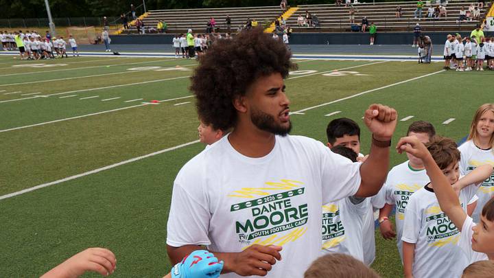 Oregon quarterback Dante Moore huddles a group of kids during a youth football camp at Marist Catholic High School on June 20, 2026, in Eugene, Oregon. Oregon quarterback Dante Moore huddles a group of kids during a youth football camp at Marist Catholic High School on June 20, 2026, in Eugene, Oregon.