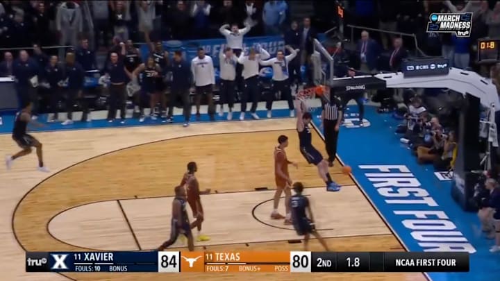 Xavier's Zach Freemantle hangs from the rim after a dunk in Xavier's 84–80 win over Texas.