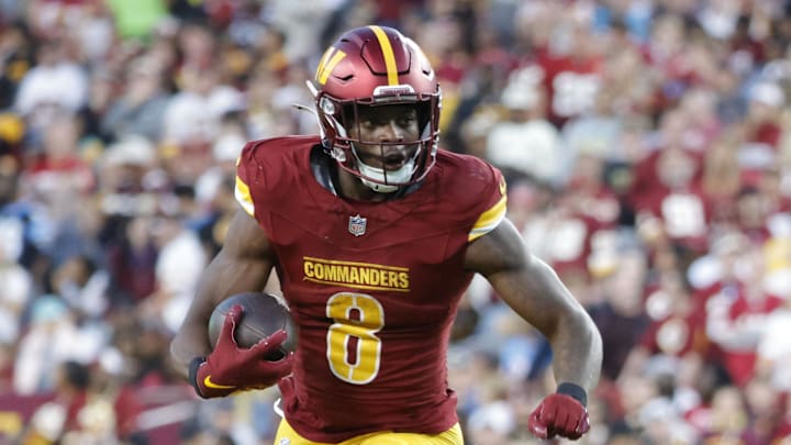 Oct 20, 2024; Landover, Maryland, USA; Washington Commanders running back Brian Robinson Jr. (8) carries the ball as Carolina Panthers cornerback Michael Jackson (2) and Panthers linebacker DJ Johnson (52) defends during the second half at Northwest Stadium. Mandatory Credit: Amber Searls-Imagn Images