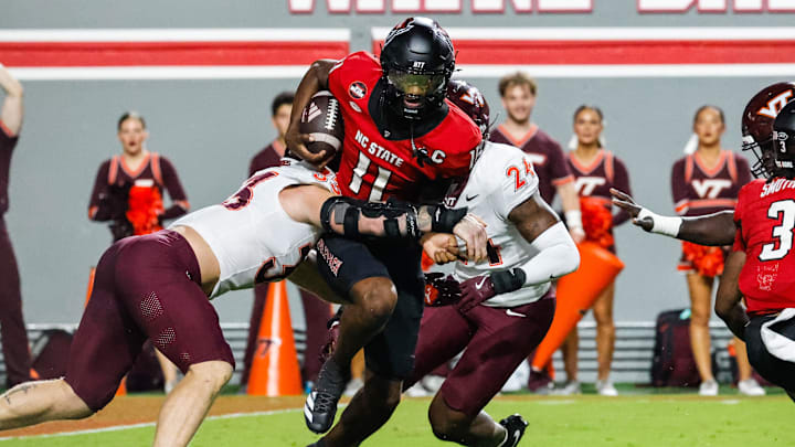 Sep 27, 2025; Raleigh, North Carolina, USA;  North Carolina State Wolfpack quarterback CJ Bailey (11) attempts to run the ball but tackled by Virginia Tech Hokies defensive lineman Ben Bell (33) and linebacker Jaden Keller (24)  during the first half of the game at Carter-Finley Stadium. Mandatory Credit: Jaylynn Nash-Imagn Images