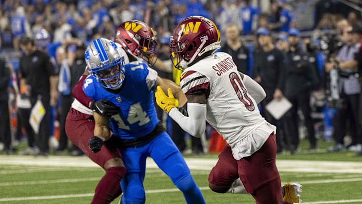 Washington Commanders corner back Mike Sainristil (0) runs the ball defended by Lions WR Amon-Ra St. Brown (14) 