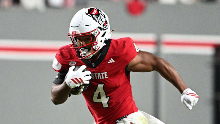 Nov 1, 2025; Raleigh, North Carolina, USA;  North Carolina State Wolfpack running back Jayden Scott (4) runs the ball around Georgia Tech Yellow Jackets linebacker E.J. Lightsey (2) during the first quarter at Carter-Finley Stadium. Mandatory Credit: Zachary Taft-Imagn Images