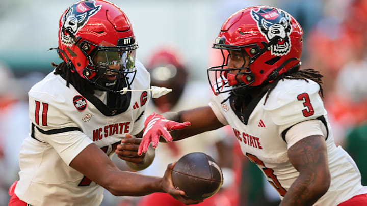 Nov 15, 2025; Miami Gardens, Florida, USA; NC State Wolfpack quarterback CJ Bailey (11) hands off the football to running back Hollywood Smothers (3) during the first quarter at Hard Rock Stadium. Mandatory Credit: Sam Navarro-Imagn Images