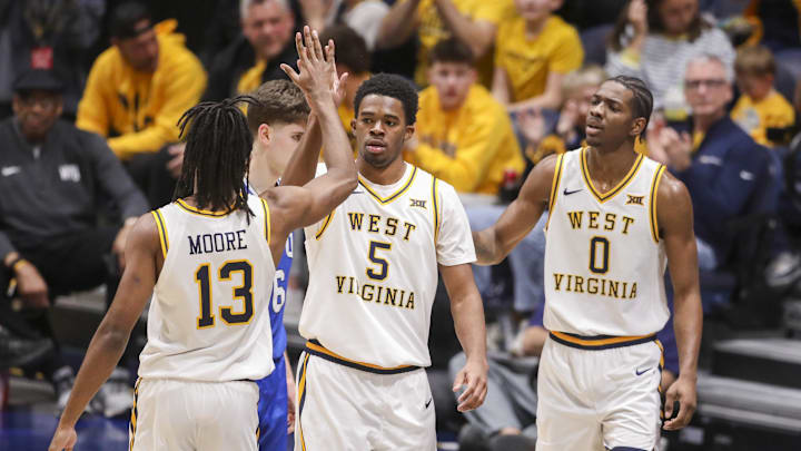 Feb 28, 2026; Morgantown, West Virginia, USA; West Virginia Mountaineers forward DJ Thomas (5) celebrates with West Virginia Mountaineers guard Chance Moore (13) during the second half against the BYU Cougars at Hope Coliseum. Mandatory Credit: Ben Queen-Imagn Images