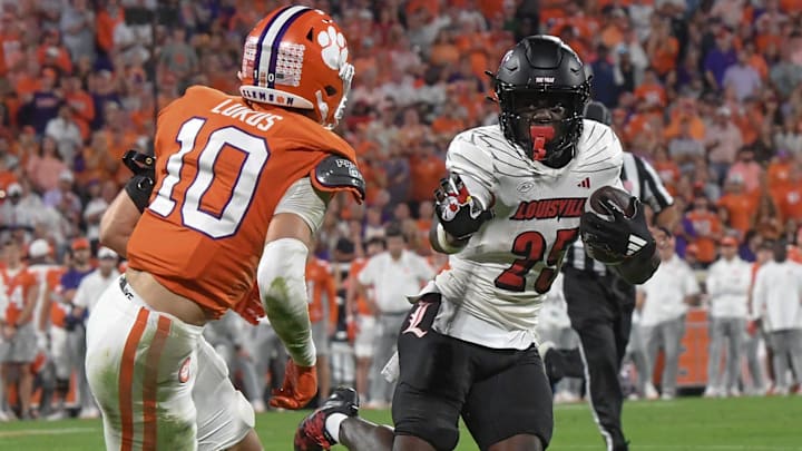 Nov 2, 2024; Clemson, South Carolina, USA; Louisville Cardinals running back Isaac Brown (25) runs the ball against Clemson Tigers cornerback Jeadyn Lukus (10) during the second quarter at Memorial Stadium. Mandatory Credit: Ken Ruinard-Imagn Images