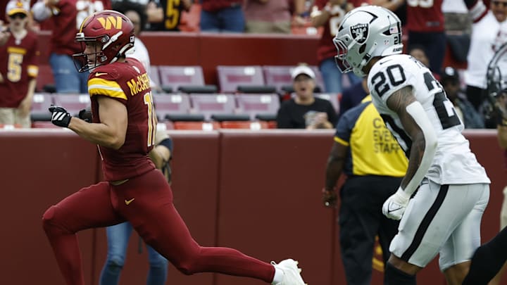 Sep 21, 2025; Landover, Maryland, USA; Washington Commanders wide receiver Luke McCaffrey (11) runs with the ball after making a catch en route to a touchdown as Las Vegas Raiders safety Isaiah Pola-Mao (20) chases during the fourth quarter at Northwest Stadium. Mandatory Credit: Geoff Burke-Imagn Images