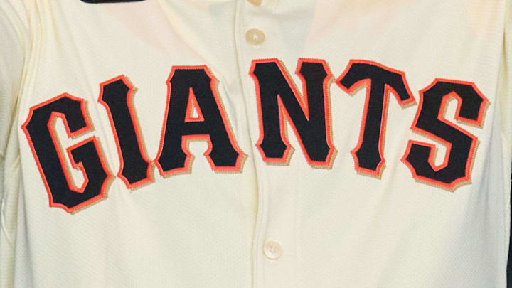 Dec 12, 2024; San Francisco, CA, USA; San Francisco Giants shortstop Willy Adames puts on his Giants jersey and hat during his introductory press conference with president of baseball operations Buster Posey at Oracle Park. Dec 12, 2024; San Francisco, CA, USA; San Francisco Giants shortstop Willy Adames puts on his Giants jersey and hat during his introductory press conference with president of baseball operations Buster Posey at Oracle Park.