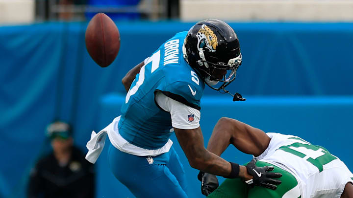 Jacksonville Jaguars wide receiver Dyami Brown (5) turns over the ball as he is hit by New York Jets cornerback Brandon Stephens (21) during the fourth quarter of an NFL football matchup at EverBank Stadium, Sunday, Dec. 14, 2025, in Jacksonville, Fla. The Jaguars defeated the Jets 48-20.