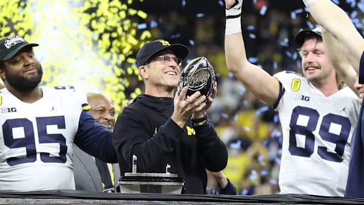 Dec. 4, 2021: Michigan coach Jim Harbaugh raises the trophy after the Wolverines' 42-3 win over Iowa