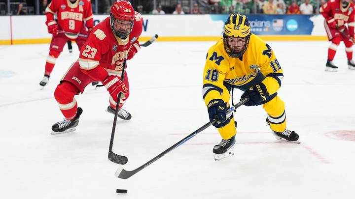 Apr 9, 2026; Las Vegas, Nevada; Denver defenseman Eric Pohlkamp and Michigan Wolverines forward Jayden Perron battle for the puck in the third period in the Frozen Four.