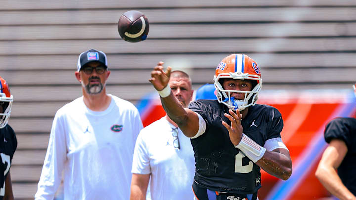 Florida Gators quarterback DJ Lagway throws a pass in front of quarterbacks coach Ryan O'Hara and head coach Billy Napier during position drills.