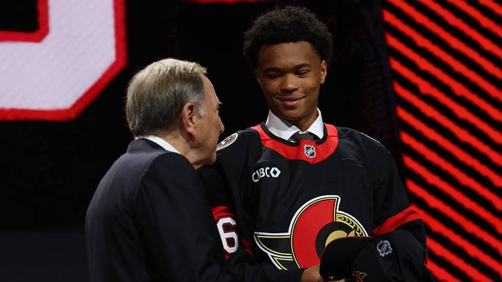 Jun 26, 2026; Buffalo, New York, USA; Jaxson Cover reacts beside NHL commissioner Gary Bettman after being selected with the thirty second pick in the first round of the 2026 NHL Draft by the Ottawa Senators at KeyBank Center. Mandatory Credit: Timothy T. Ludwig-Imagn Images