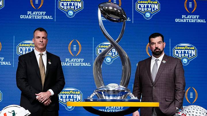 Ohio State Buckeyes head coach Ryan Day, right, and Miami (FL) Hurricanes head coach Mario Cristobal pose with the Field Scovell Trophy after talking to media during a Cotton Bowl press conference at AT&T Stadium in Arlington, Texas prior to their College Football Playoff quarterfinal matchup on Dec. 30, 2025.