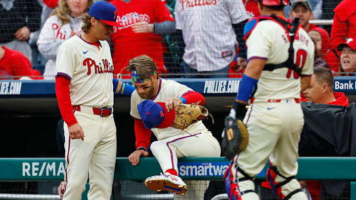 Philadelphia Phillies second baseman Bryson Stott helps Bryce Harper out of the camera well after a scary fall on Saturday