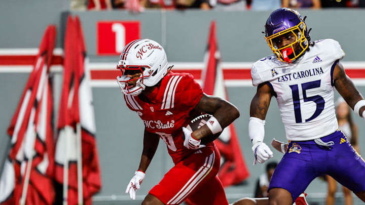 Aug 28, 2025; Raleigh, North Carolina, USA; North Carolina State Wolfpack wide receiver Wesley Grimes (6) scores a touchdown past East Carolina Pirates defensive back Jordy Lowery (15) during the first half of the game at Carter-Finley Stadium. Mandatory Credit: Jaylynn Nash-Imagn Images