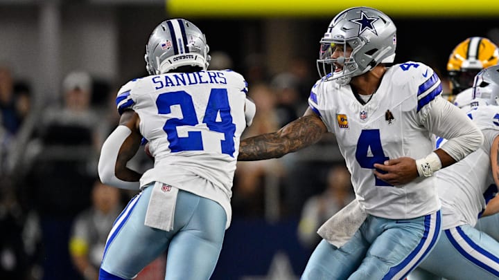 Dallas Cowboys quarterback Dak Prescott (4) hands the ball off to running back Miles Sanders (24) during the game between the Dallas Cowboys and the Green Bay Packers at AT&T Stadium.