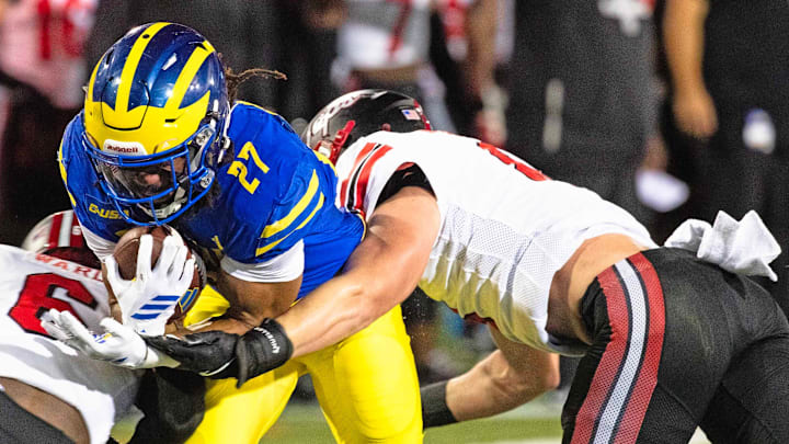 Delaware Blue Hens running back Jo Silver (27) hangs on to the ball as he is flanked by Western Kentucky defensive back Nazir Ward (6) and linebacker Miller Malone (8) for the takedown during Delaware's first home CUSA football game, which was nationally televised, at Delaware Stadium in Newark on Oct. 3, 2025. Western Kentucky won 27-24.