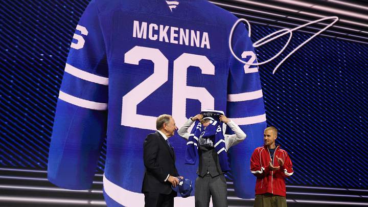 Jun 26, 2026; Buffalo, New York, USA; Gavin McKenna puts on a sweater beside NHL commissioner Gary Bettman and singer Justin Bieber after being selected with the first pick in the first round of the 2026 NHL Draft by the Toronto Maple Leafs at KeyBank Center. Mandatory Credit: Timothy T. Ludwig-Imagn Images