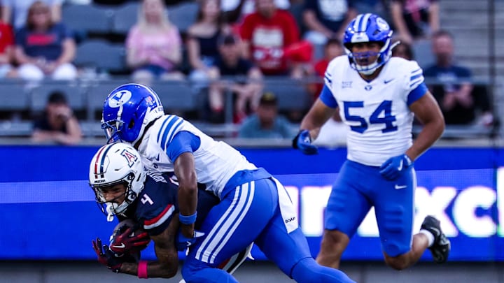 Oct 11, 2025; Tucson, Arizona, USA; Brigham Young Cougars cornerback Evan Johnson (0) tackles Arizona Wildcats wide receiver Kris Hutson (4) during the first quarter of the game at Arizona Stadium. Mandatory Credit: Aryanna Frank-Imagn Images Oct 11, 2025; Tucson, Arizona, USA; Brigham Young Cougars cornerback Evan Johnson (0) tackles Arizona Wildcats wide receiver Kris Hutson (4) during the first quarter of the game at Arizona Stadium. Mandatory Credit: Aryanna Frank-Imagn Images