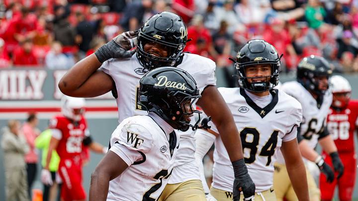 Wake Forest running back Deuce Lawrence (22) celebrates a touchdown with offensive lineman Tolu Olajide against NC State.