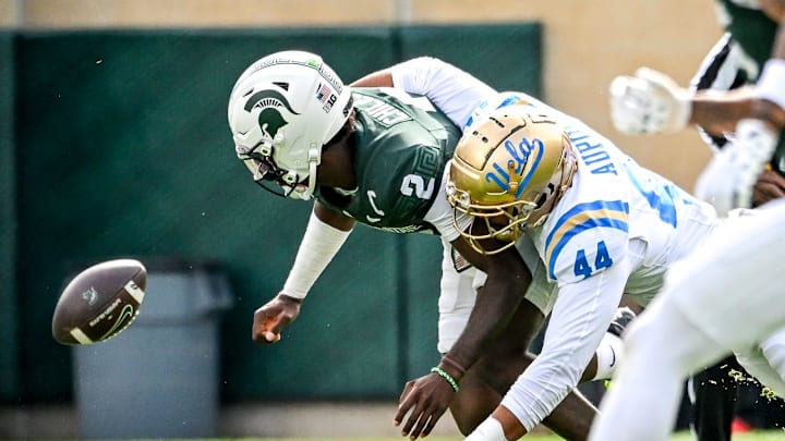 Michigan State's Aidan Chiles, left, fumbles after a hit by UCLA's Devin Aupiu during the second quarter on Saturday, Oct. 11, 2025, at Spartan Stadium in East Lansing.