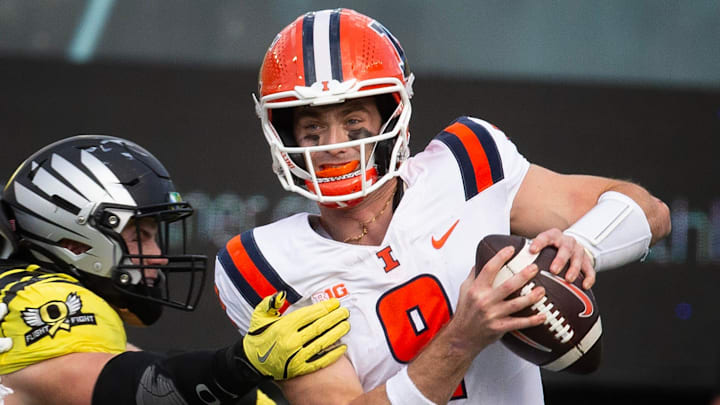 Oregon’s Bryce Boettcher, left, gets a hand on Illinois quarterback Luke Altmyer during the third quarter at Autzen Stadium.