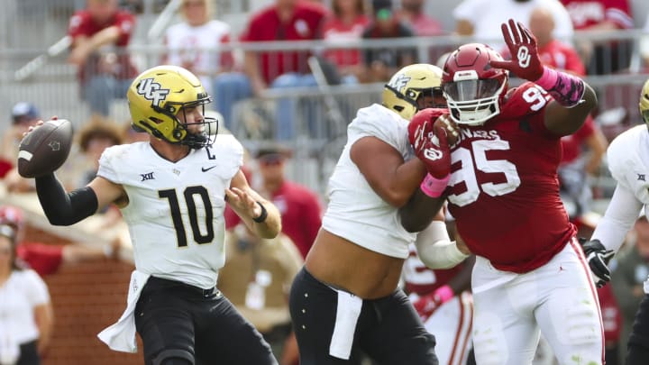 Oct 21, 2023; Norman, Oklahoma, USA;  UCF Knights quarterback John Rhys Plumlee (10) throws as Oklahoma's Da'Jon Terry pressures.