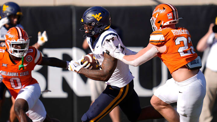 West Virginia Mountaineers running back CJ Donaldson Jr. (4) runs between Oklahoma State Cowboys safety Kobe Hylton (0) and inebacker Jeff Roberson (22) to score a touchdown during a college football game between the Oklahoma State Cowboys (OSU) and the West Virginia Mountaineers at Boone Pickens Stadium in Stillwater, Okla., Saturday, Oct. 5, 2024. West Virginia Mountaineers running back CJ Donaldson Jr. (4) runs between Oklahoma State Cowboys safety Kobe Hylton (0) and inebacker Jeff Roberson (22) to score a touchdown during a college football game between the Oklahoma State Cowboys (OSU) and the West Virginia Mountaineers at Boone Pickens Stadium in Stillwater, Okla., Saturday, Oct. 5, 2024.