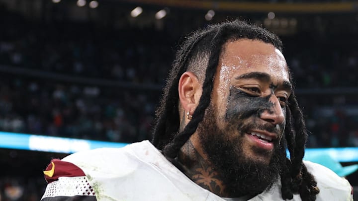Washington Commanders linebacker Frankie Luvu shakes hands with Miami Dolphins player Jonah Savaiinaea.