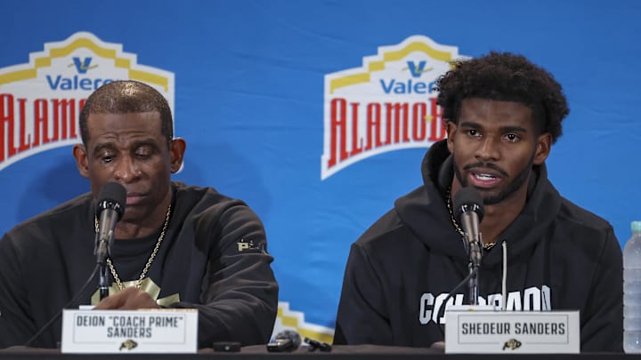Dec 28, 2024; San Antonio, TX, USA; Colorado Buffaloes head coach Deion Sanders and quarterback Shedeur Sanders (2) talk with the media after the game against the Brigham Young Cougars at Alamodome. Mandatory Credit: Troy Taormina-Imagn Images