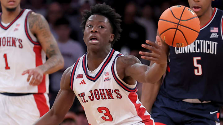 Mar 14, 2026; New York, NY, USA; St. John's Red Storm guard Joson Sanon (3) chases after a loose ball against Connecticut Huskies guard Solo Ball (1) and center Tarris Reed Jr. (5) during the second half of the men's Big East Conference Tournament Championship game at Madison Square Garden. Mandatory Credit: Brad Penner-Imagn Images