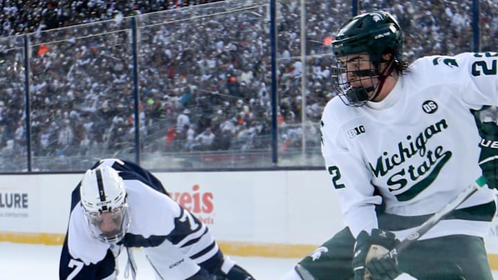Jan 31, 2026; State College, PA, USA; Michigan State Spartans forward Porter Martone (22) moves the puck against Penn State Nittany Lions defenseman Jackson Smith (7) during the second period at Beaver Stadium. Mandatory Credit: Matthew O'Haren-Imagn Images