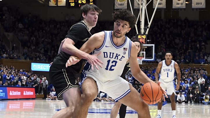 Jan 24, 2026; Durham, North Carolina, USA; Duke Blue Devils forward Cameron Boozer (12) controls the ball in front of Wake Forest Demon Deacons forward Cooper Schwieger (13) during the second half at Cameron Indoor Stadium. Mandatory Credit: Rob Kinnan-Imagn Images