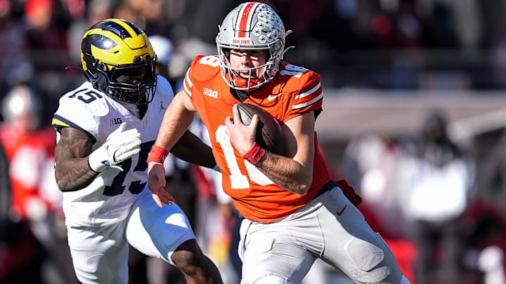 Ohio State quarterback Will Howard (18) runs against Michigan linebacker Ernest Hausmann (15) during the first half at Ohio Stadium in Columbus, Ohio on Saturday, Nov. 30, 2024.